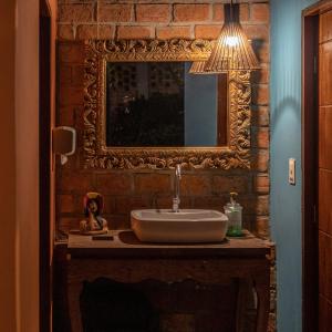 La salle de bains est pourvue d'un lavabo et d'un miroir sur un mur en briques. dans l'établissement JasmiManga Pousada, à Caruaru