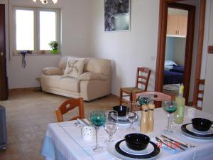 a living room with a table with plates and wine glasses at Lina apartments in Ginosa Marina