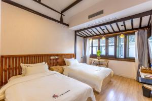 twee bedden in een kamer met twee ramen bij Tongli 1917 Best South Inn in Suzhou