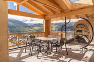 a porch with a table and chairs and a swing at Apartmentresort MyLodge in Schladming