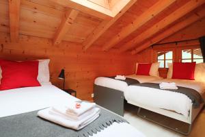 two beds in a room with wooden walls at Chalet La Pala in Val-d'Illiez