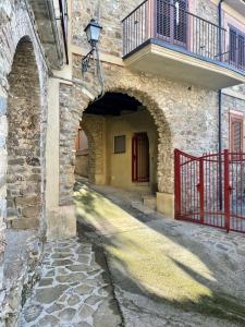 an alley in a stone building with a red gate at La Casa del Nonno in Torchiara