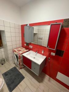 a bathroom with a sink and a red wall at La Casa del Nonno in Torchiara