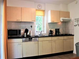 a kitchen with wooden cabinets and a microwave at Quietly located holiday home against the Lemelerberg in Lemele