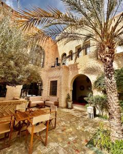 a patio with a table and a palm tree in front of a building at Dar Tozeur in Tozeur