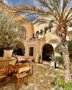 un patio con tavolo e palma di fronte a un edificio di Dar Tozeur a Tozeur