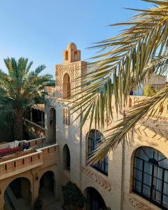 a building with a clock tower and a palm tree at Dar Tozeur in Tozeur