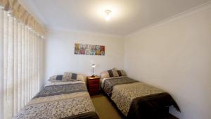 a bedroom with two beds and a window at 1 - 57 Witonga Drive, Yamba in Yamba