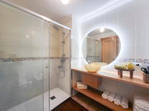 uma casa de banho com um chuveiro, um lavatório e um espelho. em MEDANO4YOU La Terraza De Isa em La Tejita