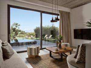 a living room with a couch and a table and a large window at Galena Verde Luxury Villas, By ThinkVilla in Akrotiri