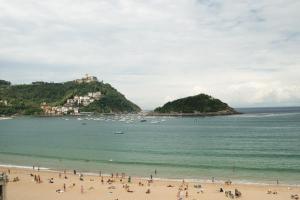 a group of people on a beach with boats in the water at Hotel Niza in Donostia-San Sebastián