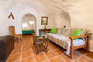 een woonkamer met een bank en een tafel bij Cuevas El Abanico - VTAR vivienda turística de alojamiento rural in Granada