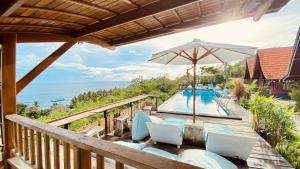 een terras met stoelen en een parasol en een zwembad bij Daphila Cottage in Nusa Penida