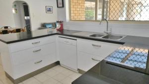 a kitchen with white cabinets and a sink at 25 Admiralty Court, Yamba in Yamba