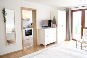 a white bedroom with a tv and a mirror at Ferienhaus Carl in Schluchsee