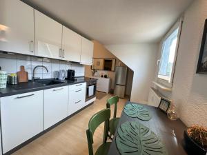 a kitchen with white cabinets and a table with green chairs at Traumwohnung - Charmante Citywohnung nahe Hauptbahnhof in Koblenz