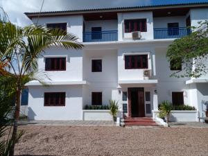 a white building with black windows and a palm tree at Ban Saylomleng Residence in Vientiane