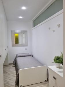 biała sypialnia z łóżkiem i lustrem w obiekcie Appartamento ORCHIDEA a Sirmione sul Lago di Garda con piscina, giardino e spiaggia con molo w Sirmione