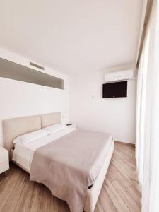 a white bedroom with a large bed and a television at Appartamento ORCHIDEA a Sirmione sul Lago di Garda con piscina, giardino e spiaggia con molo in Sirmione