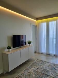 a living room with a flat screen tv on a cabinet at Appartamento ORCHIDEA a Sirmione sul Lago di Garda con piscina, giardino e spiaggia con molo in Sirmione