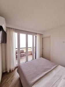 1 dormitorio blanco con 1 cama grande y balcón en Appartamento ORCHIDEA a Sirmione sul Lago di Garda con piscina, giardino e spiaggia con molo en Sirmione
