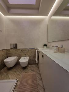 W łazience znajduje się umywalka, toaleta i lustro. w obiekcie Appartamento ORCHIDEA a Sirmione sul Lago di Garda con piscina, giardino e spiaggia con molo w Sirmione