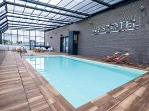 a large swimming pool with two chairs in a building at Westotel Pornic Côte de Jade in Pornic