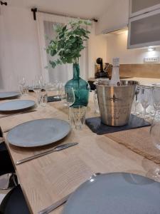 una mesa con platos y un jarrón con una botella de vino en Nalan Orrygeois, 6 pers, Astérix, CDG, CHANTILLY, en Orry-la-Ville
