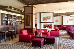un restaurant avec des chaises rouges et un bar dans l'établissement Luxory aparthotel in 4 star SPA hotel st Ivan Rilski, Bansko, à Bansko