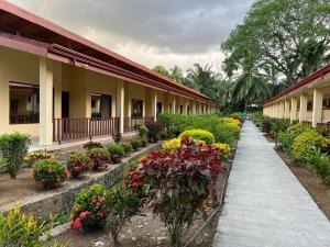 un giardino fiorito e un vialetto accanto a un edificio di La Foresta Nature Resort a Quepos