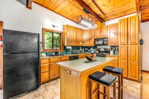 a kitchen with wooden cabinets and a black refrigerator at Tree Tops Bungalow in Guerneville