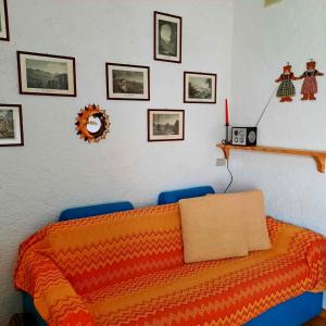 a bedroom with an orange bed and pictures on the wall at Appartamento Monte Muggio - Your Mountain Holiday in Casargo