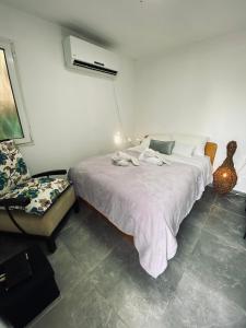 ein Schlafzimmer mit einem weißen Bett und einem Stuhl in der Unterkunft Yogo Place in Nahariyya in Naharija