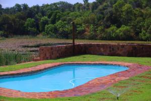 a brick retaining wall around a pool in a field at Waterberg Game Lodge in Bela-Bela +10 photos