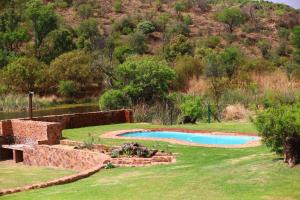 a backyard with a swimming pool and a stone wall at Waterberg Game Lodge in Bela-Bela