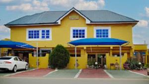 a yellow building with blue umbrellas in front of it at Golden Touch Executive Hotel in Tema