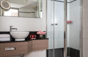 ein Bad mit einem Waschbecken und einer Dusche in der Unterkunft Leonardo Hotel Munich City Olympiapark in München