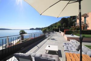 a patio with couches and tables and an umbrella at Resort Antico Verbano in Meina