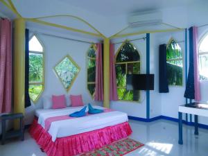a bedroom with a bed with pink and blue at MG Chateau Resort in El Nido