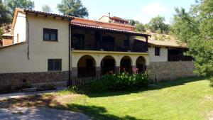 a large house with a balcony and a yard at Apartamentos rurales Alameda del Jerte in El Torno