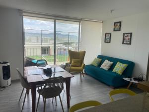 uma sala de estar com uma mesa e um sofá azul em Hermoso apartamento en club house em Ricaurte
