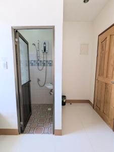 een badkamer met een douche, een toilet en een deur bij Charlina Inn Panglao in Panglao