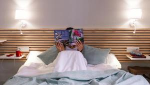 a woman laying in bed reading a book at Veranera Hostel in Estepona