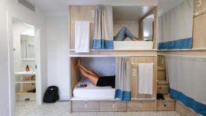 a person laying on a bed in a small room at Veranera Hostel in Estepona