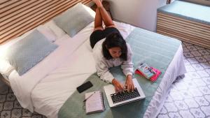 a woman laying on a bed using a laptop computer at Veranera Hostel in Estepona