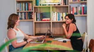 two women sitting at a table with a laptop at Veranera Hostel in Estepona