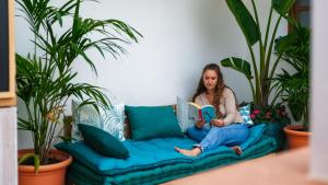 a woman sitting on a couch reading a book at Veranera Hostel in Estepona
