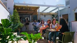 a group of women sitting at tables on a patio at Veranera Hostel in Estepona