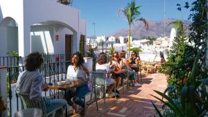 a group of people sitting at tables on a balcony at Veranera Hostel in Estepona