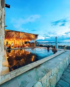 a swimming pool at a resort with a lighthouse in the background at Harbour Komodo Hotel in Labuan Bajo